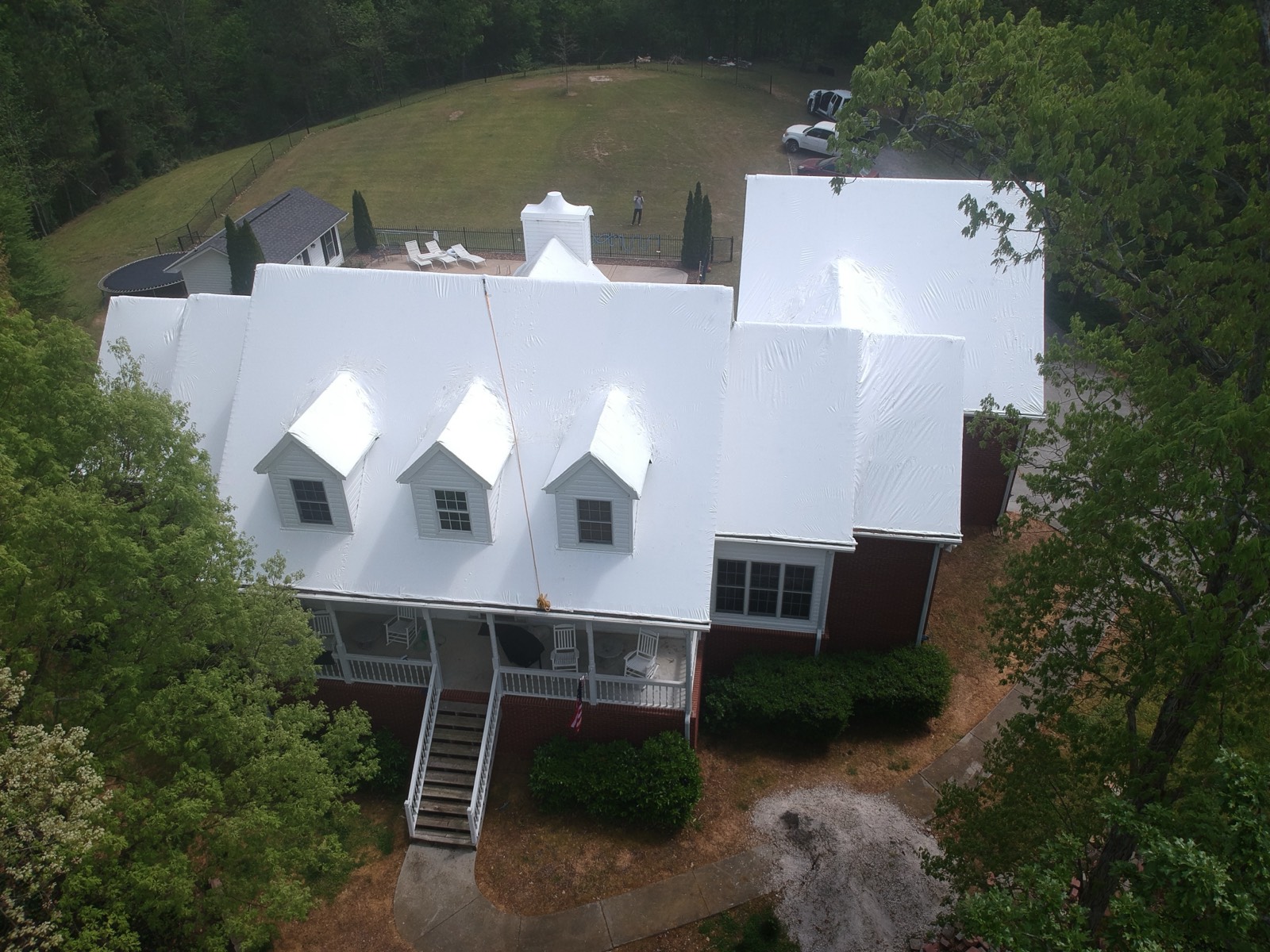 Same roof sealed watertight under a clean white stretch roofing film